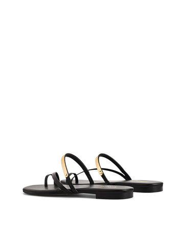 Women's black leather flat slide with gold metallic embellishment, dainty straps and toe ring